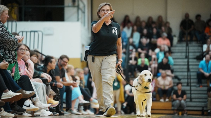 Ruby walking with Ultimate Canine trainer at pup rally